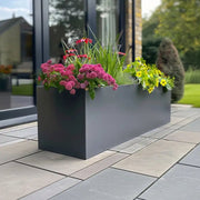 Grey planter pot filled with vibrant blooms, brightening up a balcony.